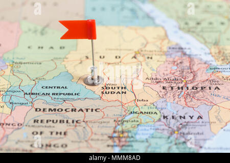 Small red flag marking the African country of  South Sudan on a world map. Stock Photo