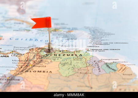 Small red flag marking the South American country of  Venezuela on a world map. Stock Photo