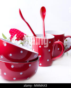 Red polka dot bowls, cups and spoons on a white background Stock Photo