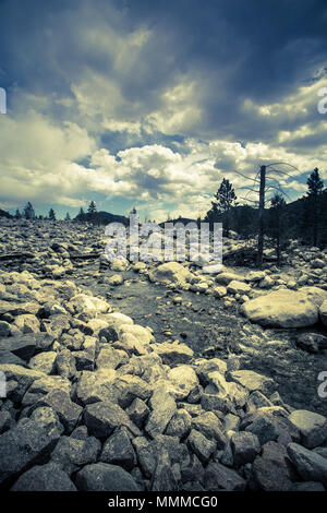 View from Rocky Mountain National Park in Colorado with stream over rock landscape, mountains and ominous sky Stock Photo