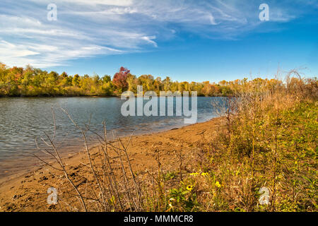 A beautiful autumn day at a small tree lined  lake in Ohio with a pretty blue sky with white puffy clouds reflecting in the water. Stock Photo