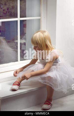 Girl 3 years old in a beautiful white dress near the winter window Stock Photo