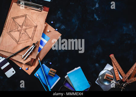Header with draftsman or designer workplace with craft paper, sketches, compasses, rulers, clipboards and pencils on a dark stone background. Top view Stock Photo