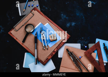 Wooden clipboard with craft paper and sketches on a designer workplace close-up. Sketches, compasses, rulers and pencils in an architect or interior d Stock Photo