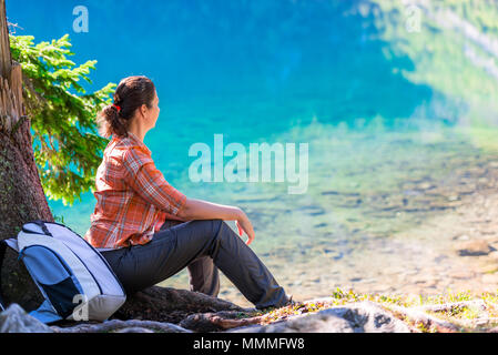 a woman sits by the Lake of the Sea Eye in the Tatra Mountains and admires Stock Photo