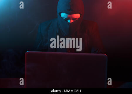 Red Led Hacker Computer Angry computer hacker in suit stealing data from laptop illuminated by ...