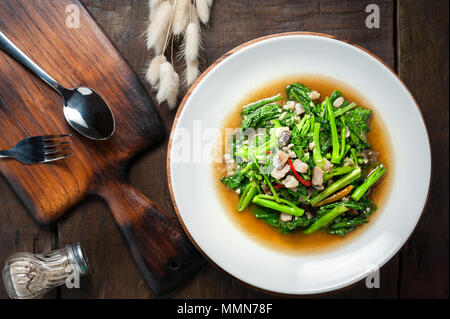 Thai food : Stir-fried kale with sun-dried salted fish on wooden table Stock Photo