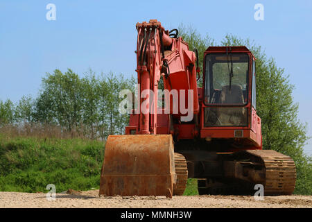 Old rusty excavator with broken window on sandy ground Stock Photo