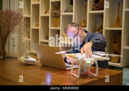 Mature man with drone and laptop in the dining room at home Stock Photo