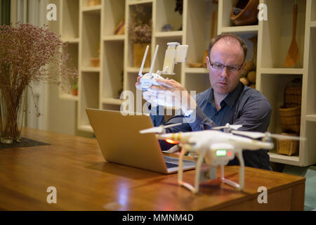 Mature man with drone and laptop in the dining room at home Stock Photo