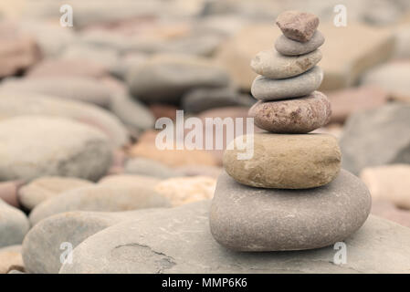 Pile of stones on a pebble beach in warm evening light. Calm peaceful zen concept Stock Photo