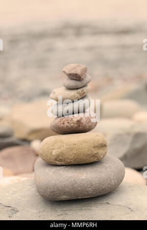 Pile of stones on a pebble beach in warm evening light. Calm peaceful zen concept Stock Photo