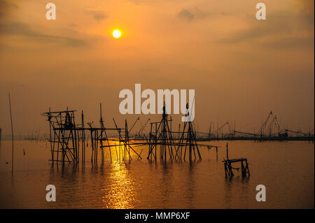Traditional bamboo and wooden fishing tools installed in rural swamp for fishing during sunset. Stock Photo