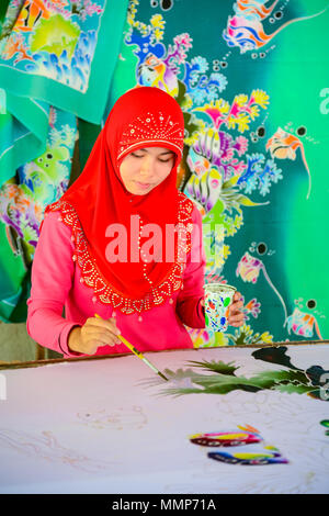 Krabi, Thailand - May 2, 2015: Beautiful Muslim woman wearing red hijab painting pattern on Batik fabric in Krabi, Thailand Stock Photo