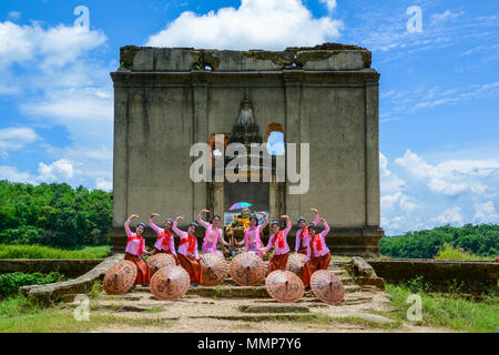 Kanchanaburi, Thailand - July 24, 2016: Beautiful teenage girls with Mon tradition dresses dancing to show tourists close to ruined Buddhist church in Stock Photo