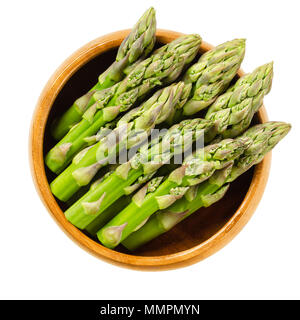 Fresh green asparagus tips in wooden bowl. Sparrow grass shoots. Cultivated Asparagus officinalis. Vegetable with thick stems and closed buds. Stock Photo