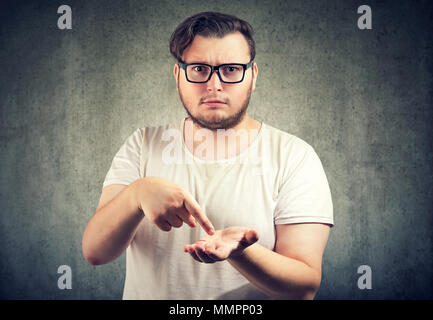 Young serious chubby man asking for more money to pay back debt Stock Photo