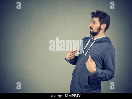Side profile of a young man pointing fingers at himself being in denial Stock Photo
