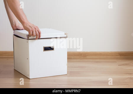 hands opening white box on the floor in empty room Stock Photo