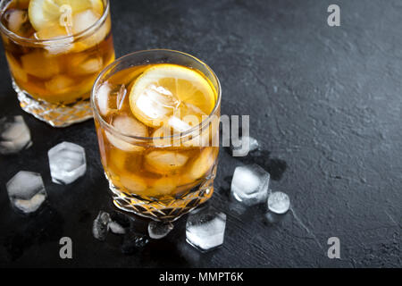 Whiskey High Ball Cocktail with lemon and ice cubes on black background, copy space. Stock Photo
