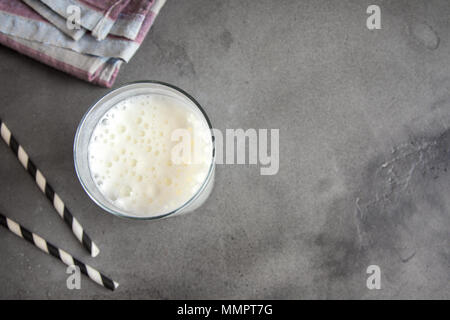 Fresh plain homemade yougurt (yogurt, youghurt, kefir, ayran, lassi) in glass with herbs over gray background, copy space. Probiotic cold fermented da Stock Photo