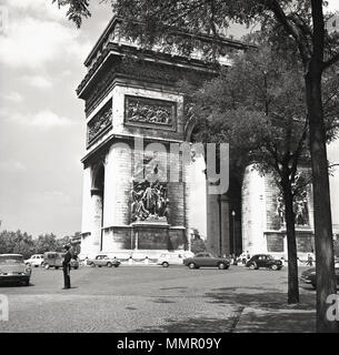 1950s, motor vehicles go around the iconic Arc de Triomphe monument in Paris, France, located at the Place de l'Etoile and the Avenue des Champ Elysees and built to celebrate the french commander, Napoleon's military victories. Stock Photo