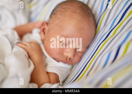 A newborn infant laying on a pillow sleeping with shallow depth of field Stock Photo