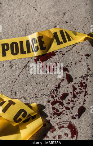Police cordon tape lies on the ground in a small amount of blood. Stock Photo