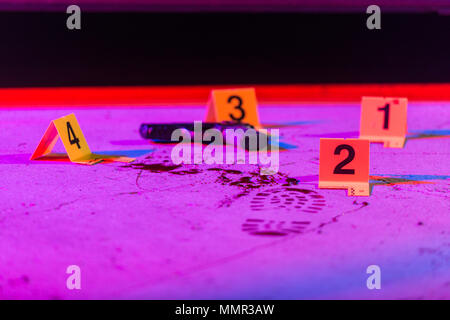 A black handgun lays on the pavement in a crime scene, marked with an evidence marker. Stock Photo