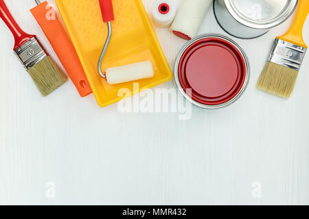 painting tools on white wooden background. paint cans, brushes and rollers with paint tray. flat view Stock Photo