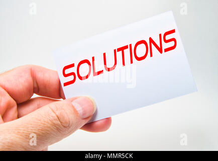 man hand holding a gray billboard with solution word written in it on a gray background Stock Photo
