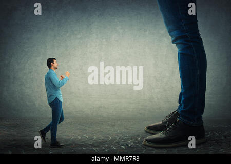 Young man holding fists ready to fight his big boss. Office confrontation. Stock Photo