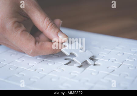 Hand placing the last jigsaw for business solution concept Stock Photo