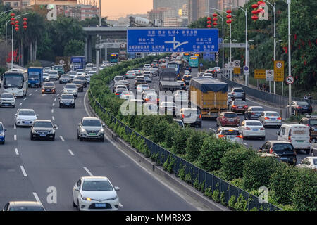 China, Shenzhen, 2018-03-09: Evening traffic in big city, cars on divided highway road, traffic jam at street, busy urban view at sunset. Stock Photo