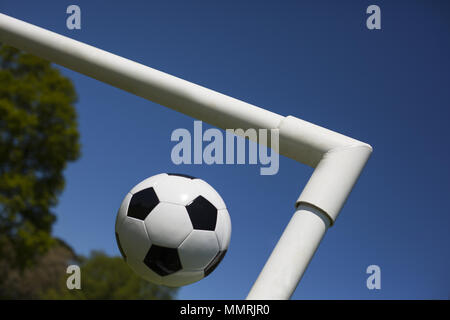 A black and white leather football at the cross of the goal posts Stock Photo