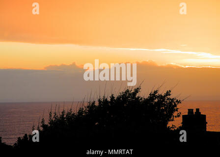 Portland. 12th May 2018.The warm colours of the setting sun over Lyme Bay at dusk, seen from a Portland garden Stock Photo