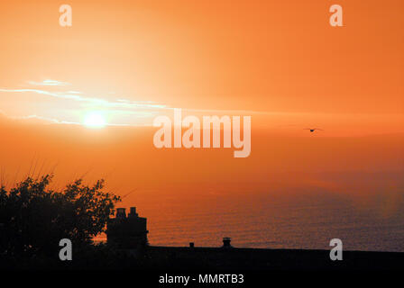 Portland. 12th May 2018.The warm colours of the setting sun over Lyme Bay at dusk, seen from a Portland garden Stock Photo