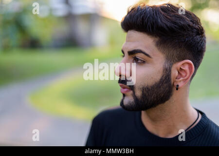 Close up profile view of young handsome Indian man thinking at t Stock Photo