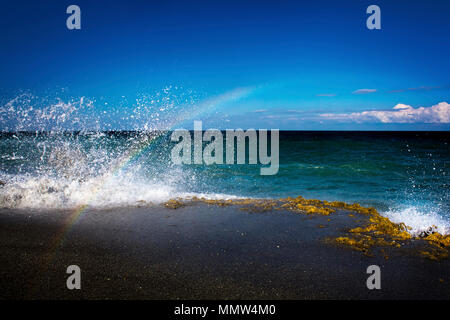 Crashing waves at Blowing Rocks Preserve in Florida create a momentary rainbow. Stock Photo