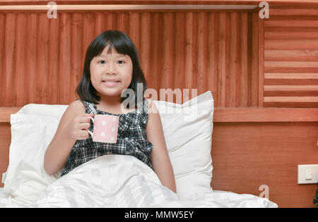 happy daughter drink milk on bed before sleep, Healthy concept Stock Photo