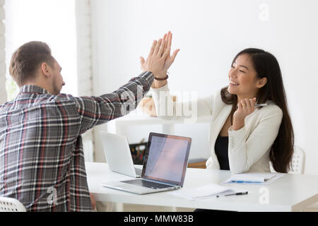 Young asian and caucasian partners giving high-five celebrating  Stock Photo