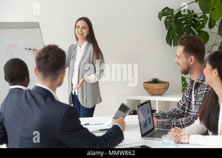 Smiling young employee giving presentation working with flipchar Stock Photo