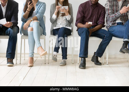 Diverse black and white people using smartphones tablets in queu Stock Photo