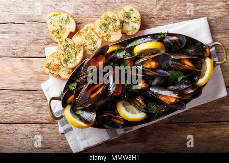 Copper pot of gourmet mussels with lemon, parsley and garlic served on a bread. Horizontal top view from above Stock Photo