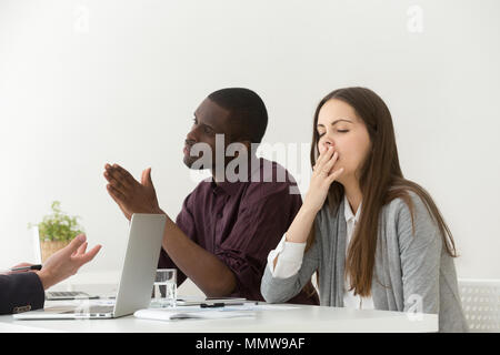 Tired bored businesswoman yawning at boring meeting with diverse Stock Photo