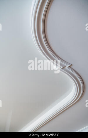 Curved decorative clay stucco relief molding on white ceiling in abstract classical style interior Stock Photo