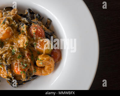 Black Spaghetti in tomato sauce with shrimp, tomato sprinkle with spices and cheese on white plate.Fresh and clean dishes look delicious and yummy Stock Photo