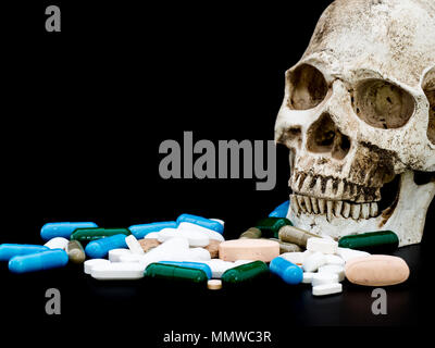 Human skull on multicolored of drug and capsule is on the black background. Close up. We are against drugs (anti drugs), cure in container for health. Stock Photo