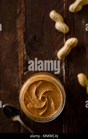 Peanut Butter in a Glass Jar with Peanuts on Wood Stock Photo