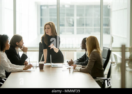 Serious woman boss talking to multiracial team at boardroom meet Stock Photo